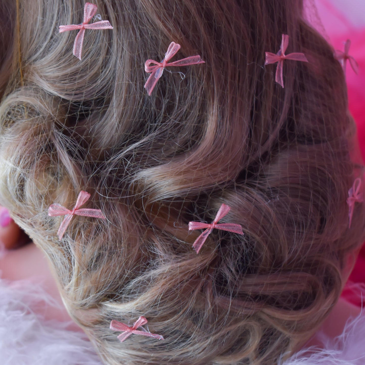 Close-up of wavy hair with pink hair clips on a pink background