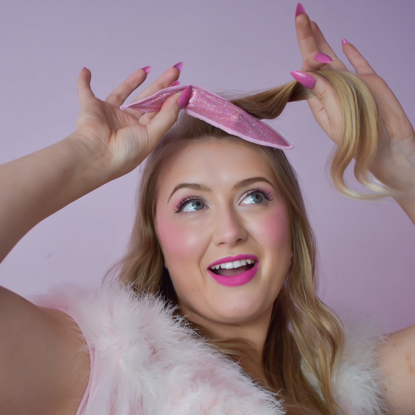 Woman with pink hair extensions and a fluffy pink headband against a light purple background