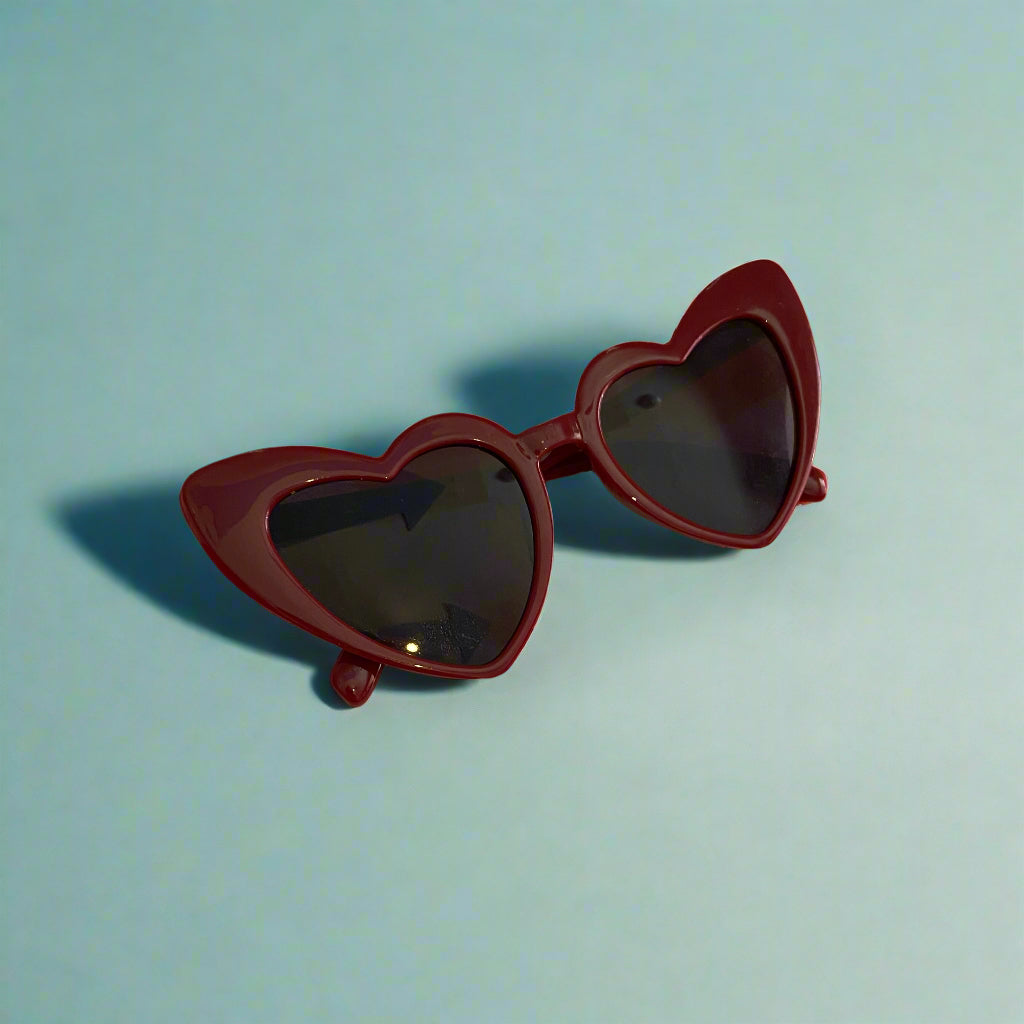 Heart-shaped sunglasses on a red and white checkered tablecloth