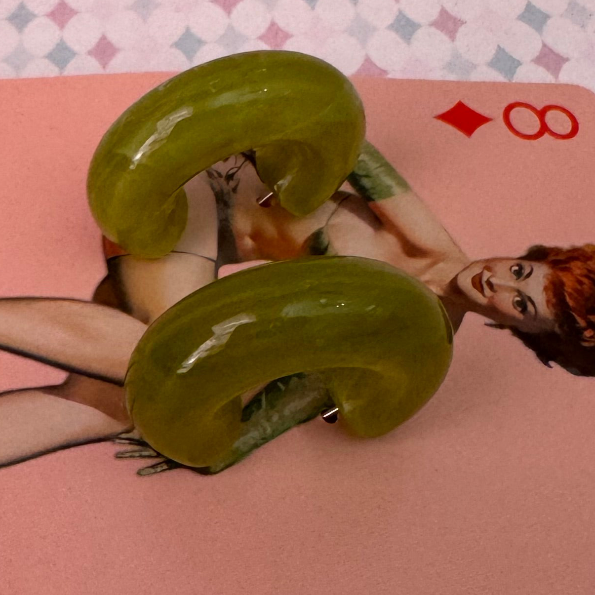 Green earrings on a card with a woman's face