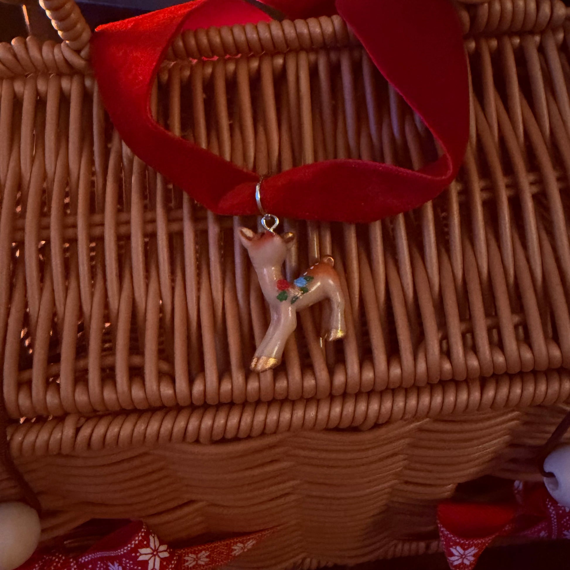 Decorative reindeer charm on a woven basket with red ribbon